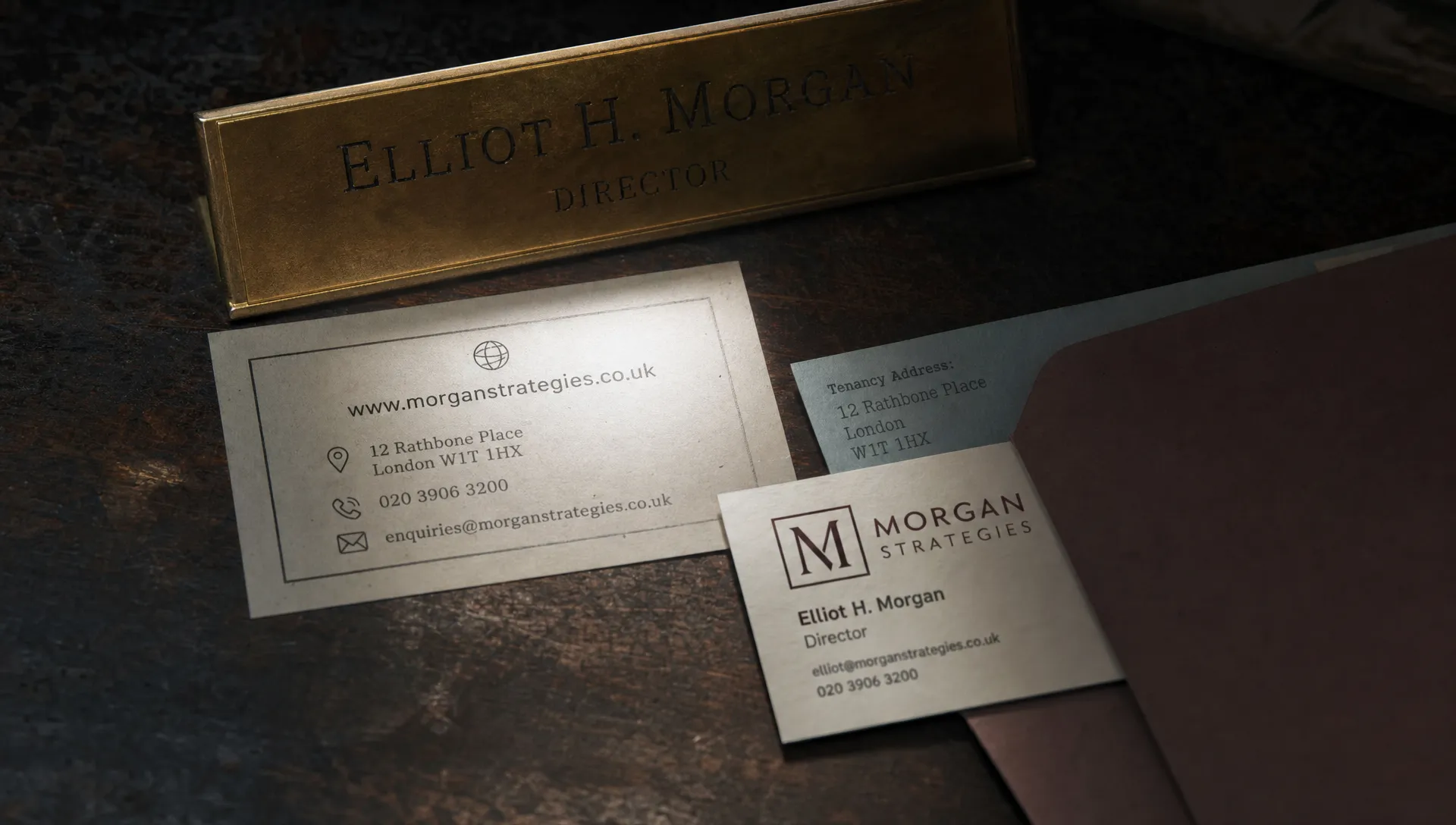 A brass nameplate, contact card and address slip on a dark desk show the facts that help Google recognise one business.