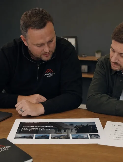 A business owner and an SEO specialist review a homepage layout and service list at a table.